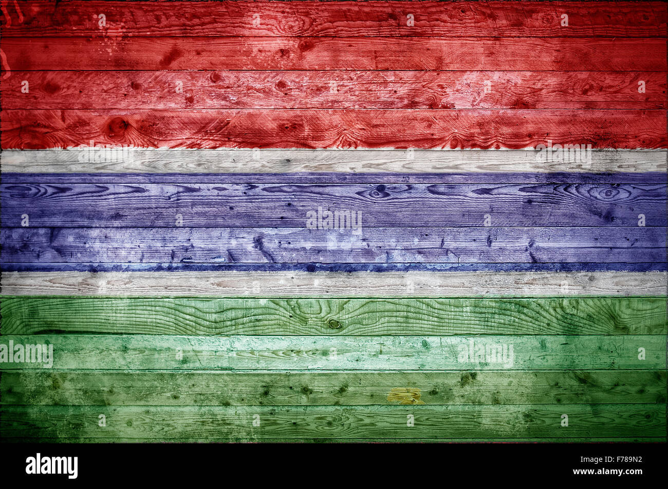 A vignetted background image of the flag of Gambia painted onto wooden boards of a wall or floor. Stock Photo