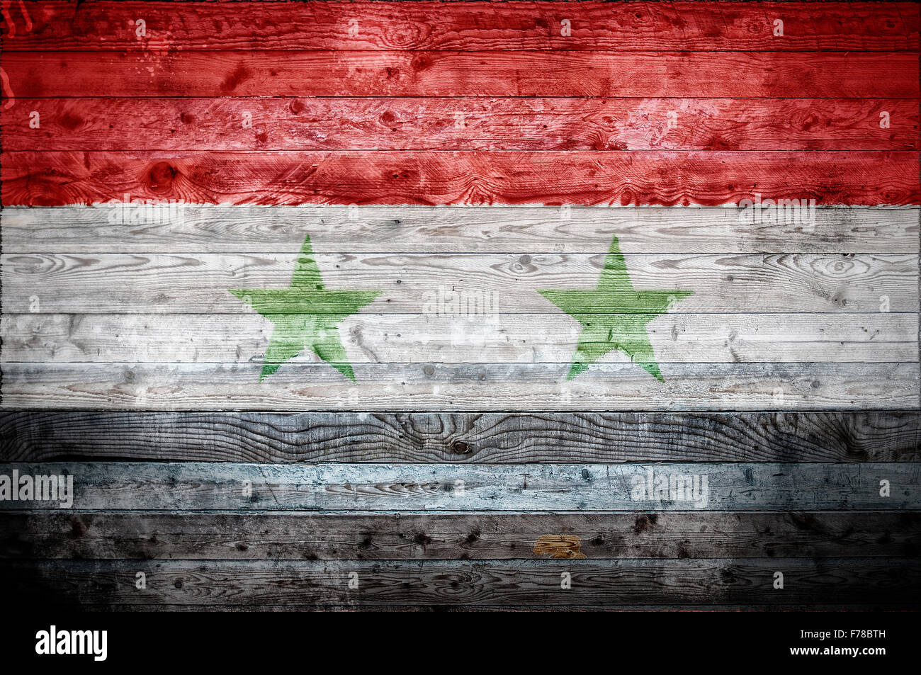 A vignetted background image of the flag of Syria onto wooden boards of a wall or floor. Stock Photo