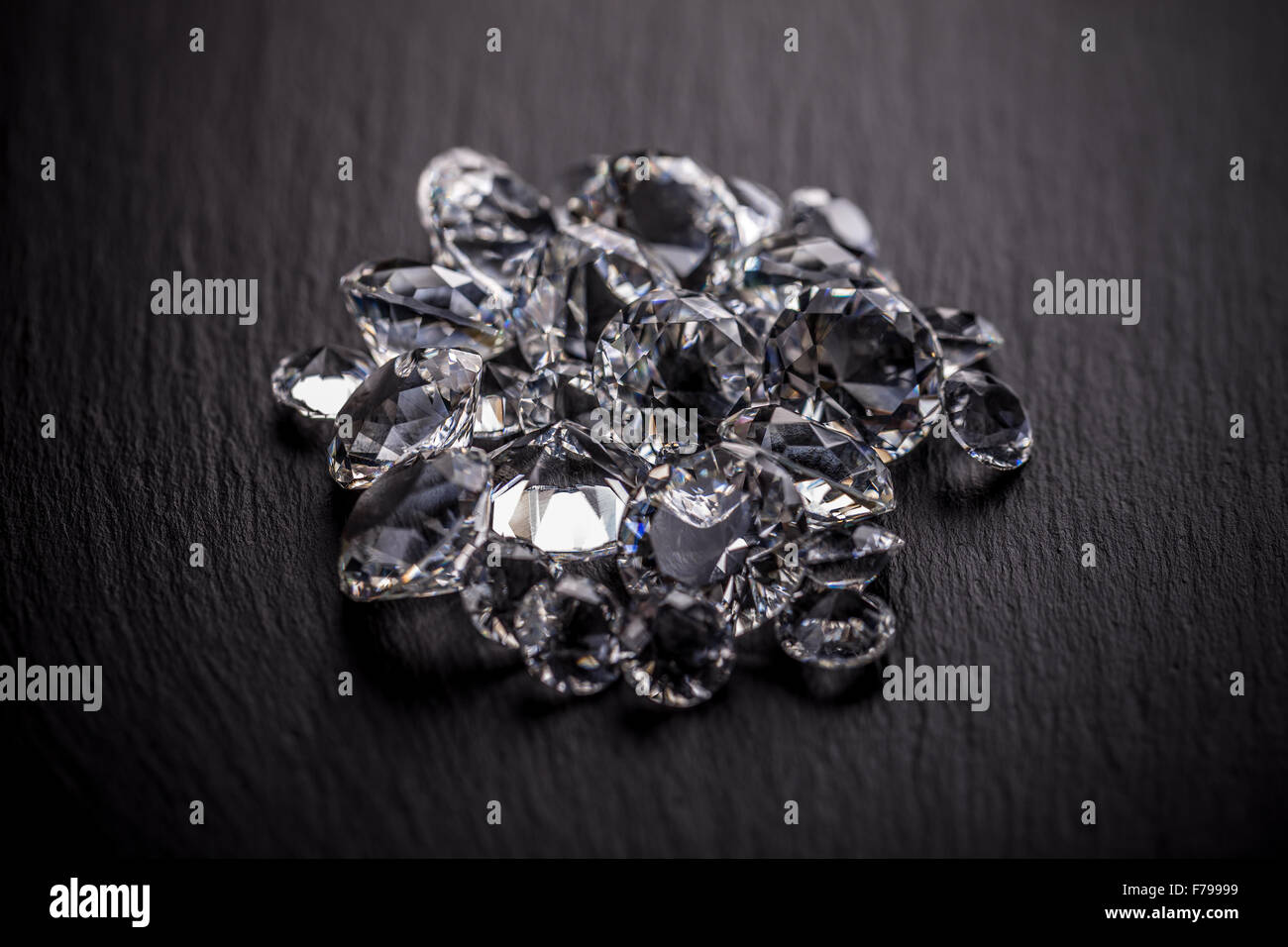 Pile of diamonds on dark metal surface Stock Photo