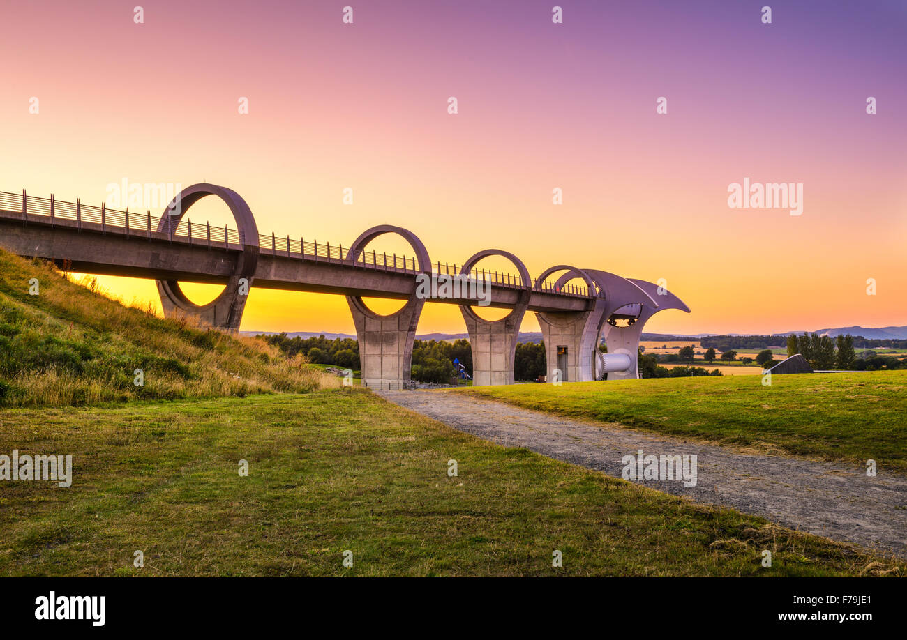 Falkirk Wheel at sunset. Falkirk Wheel is a rotating boat lift in Scotland and connects the Forth and Clyde Canal with the Union Stock Photo
