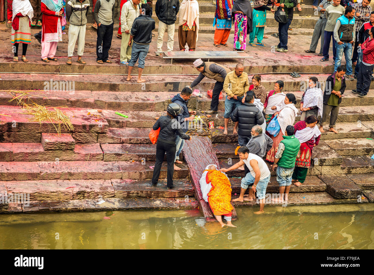 Hindu people attend a religious burial ceremony of a dead person  at the banks of Bagmati river at Pashupatinath Temple complex Stock Photo