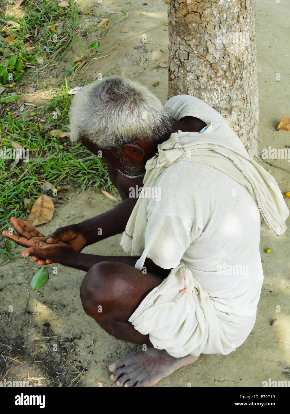 Portrait: The poor old man from India sits on the ground Stock Photo