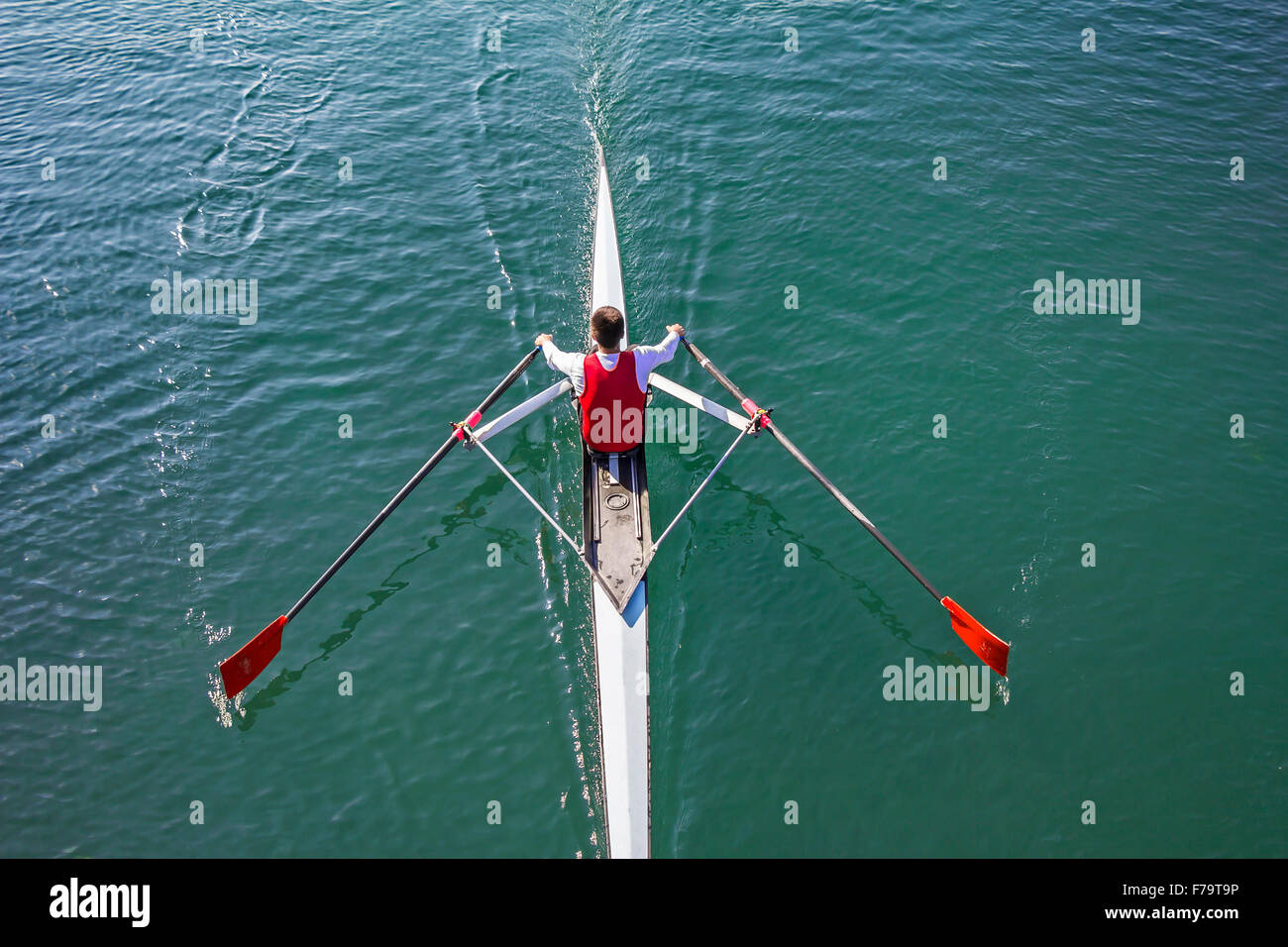 Young Man in a boat trains rowing on the tranquil lake Stock Photo