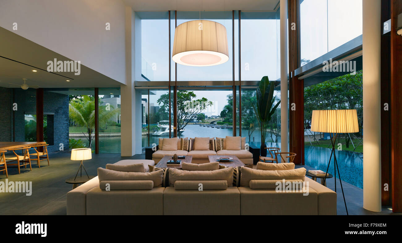 Lit double height living room in a family house in Cove Way, Sentosa, Singapore designed by Robert Greg Shand Architects Stock Photo