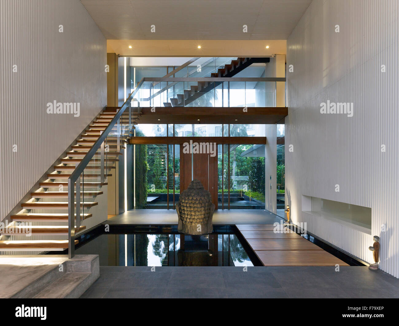 Open plan entrance hall and staircase with pool of water and Buddhist statue in Cove Way House, Sentosa, Singapore Stock Photo