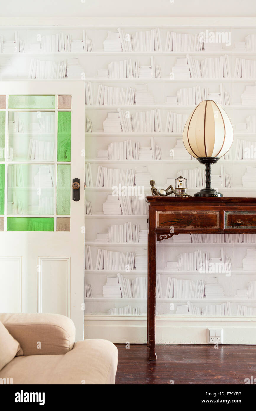Book wallpaper and vintage console in Sydney home of designer and Heritage Consultant Janine Hendry. Stock Photo