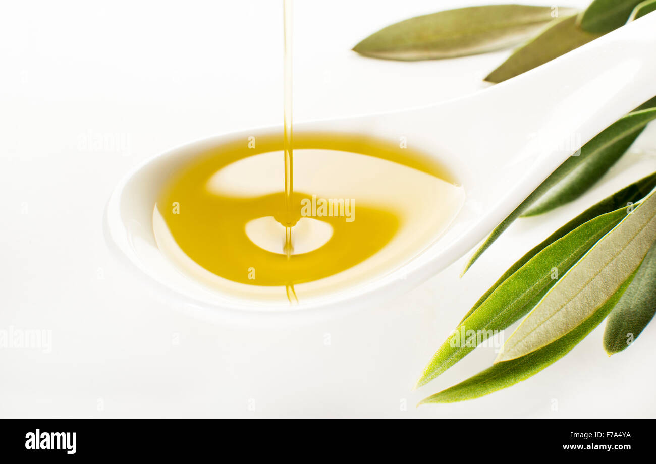 Virgin olive oil pouring on white spoon. Stock Photo