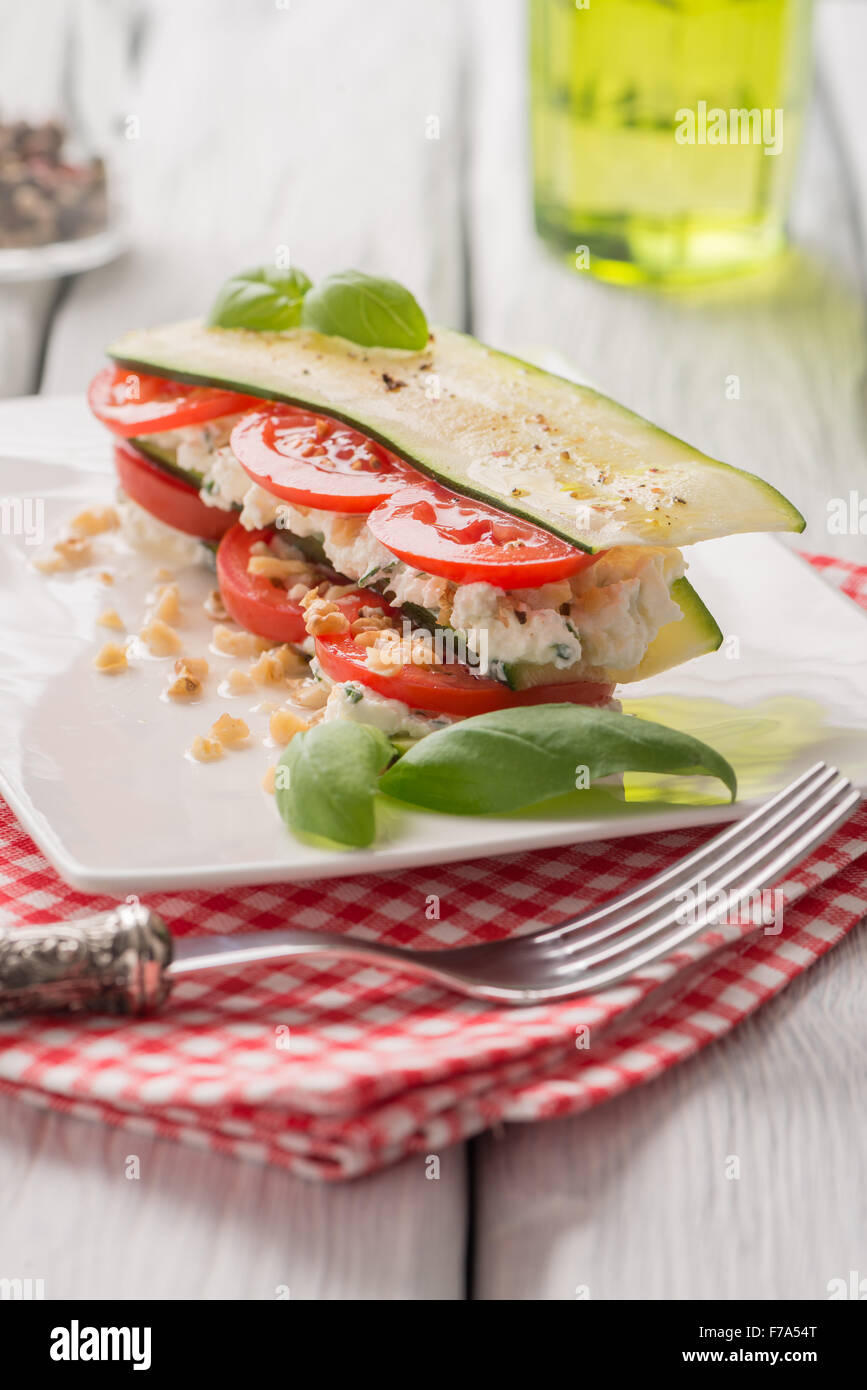Delicious Italian appetizer of tomato, zucchini slices, nuts, basil and fresh cheese. Stock Photo