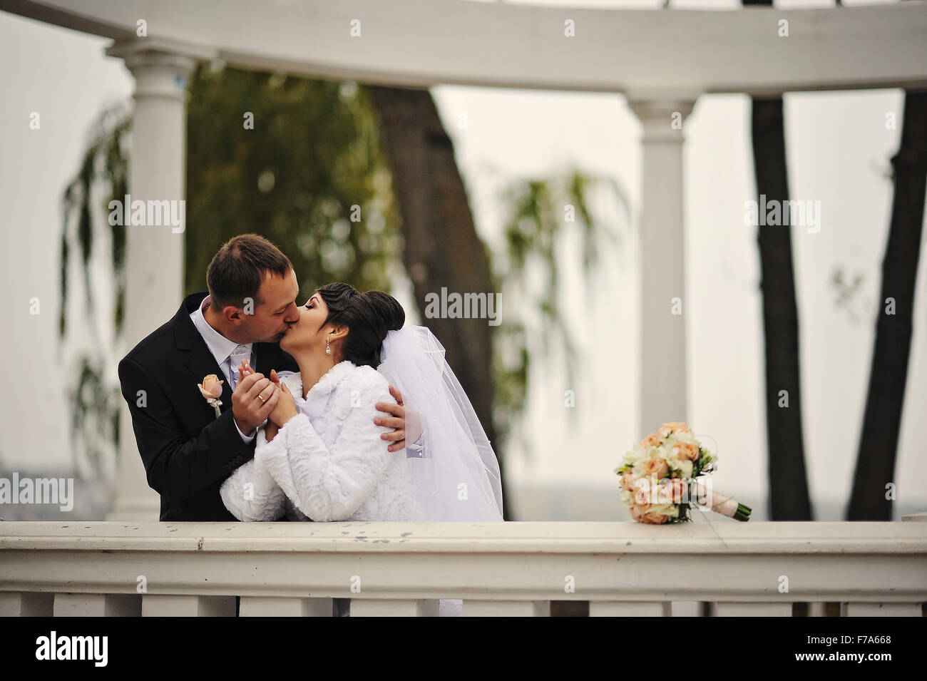 wedding couple kissing at white arch column Stock Photo - Alamy
