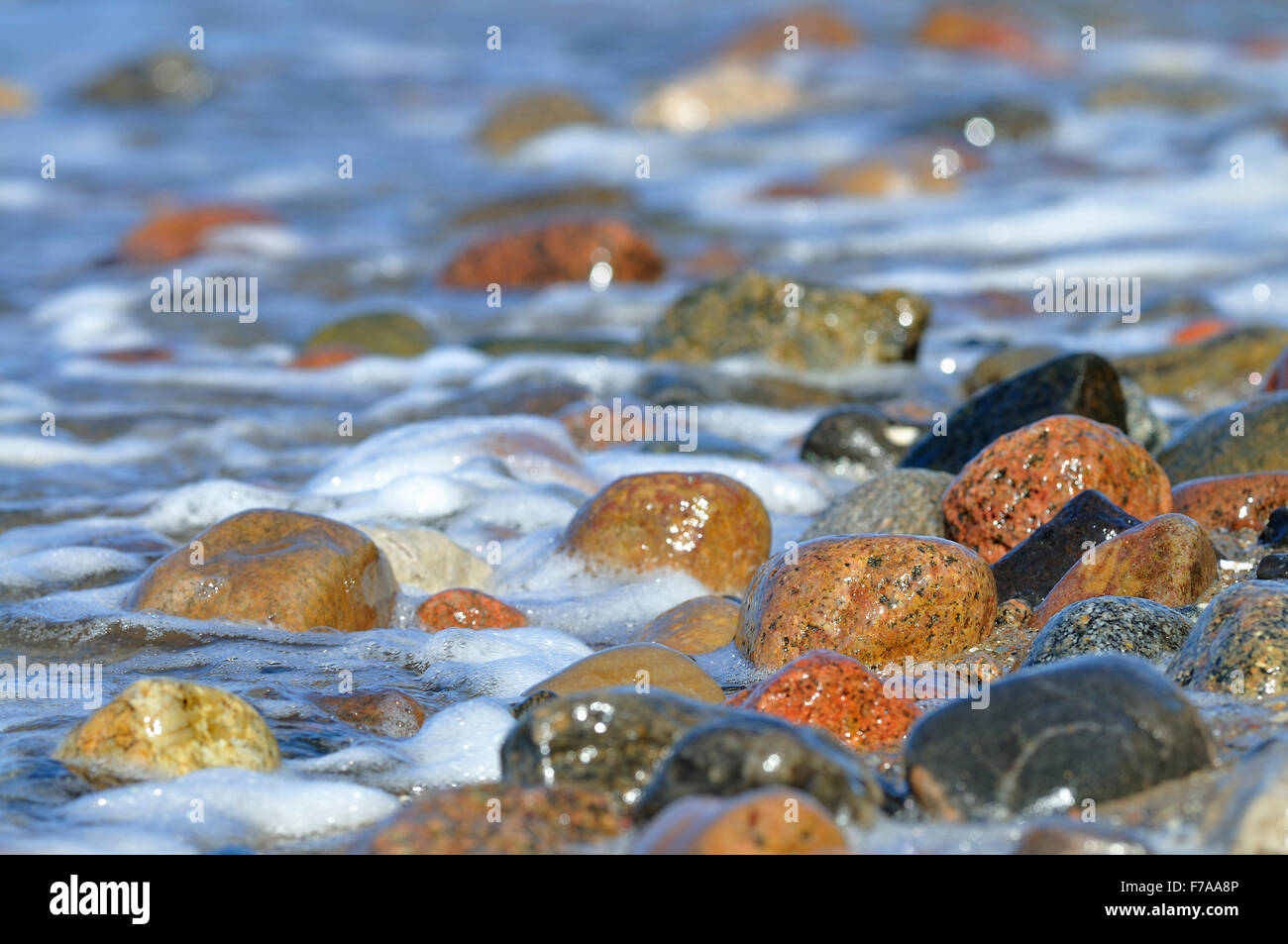 Colorful stones with splashing water, Hohes Ufer near Ahrenshoop, Fischland-Darß-Zingst, Mecklenburg-Western Pomerania, Germany Stock Photo