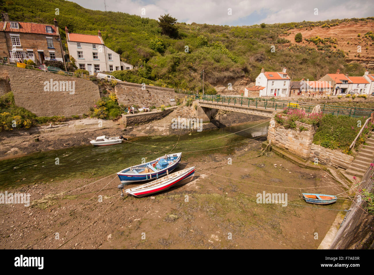 Picturesque view of Staithes fishing village in North Yorks including artists, boats and footbridge Stock Photo