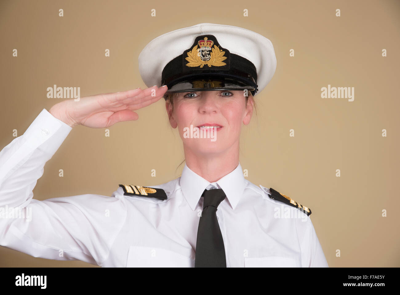 Female navy officer in uniform of a Lt Commander wearing a hat and saluting Stock Photo