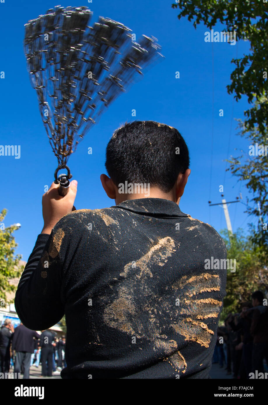 Iranian Shiite Boy Covered In Mud Is Beating Himself With Iron Chains To Commemorate Ashura, The Day Of The Death Of Imam Hussein, Kurdistan Province, Bijar, Iran Stock Photo