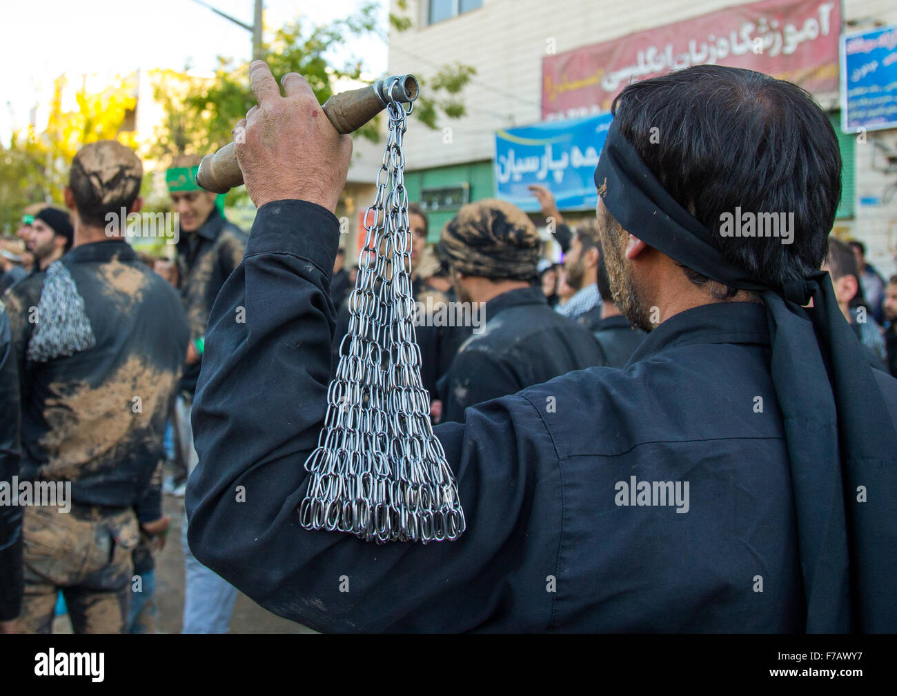 Iranian Shiite Men Covered In Mud Are Beating Themselves With Iron Chains During Ashura, The Day Of The Death Of Imam Hussein, Kurdistan Province, Bijar, Iran Stock Photo