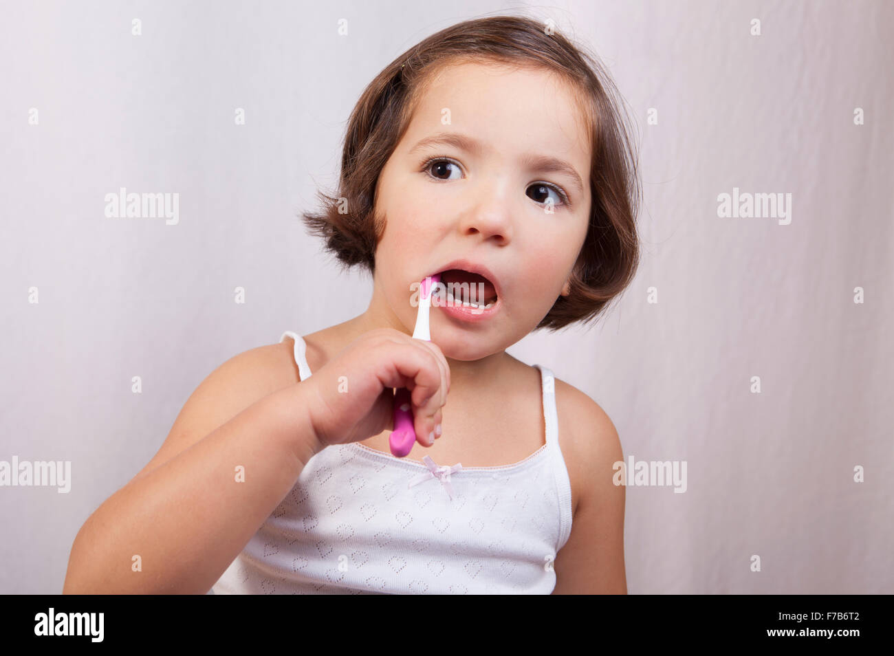 Little brown eye girl brushing her teeth. Isolated over white background Stock Photo