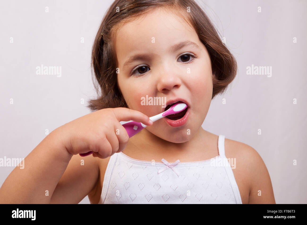 Little brown eye girl brushing her teeth. Isolated over white background Stock Photo