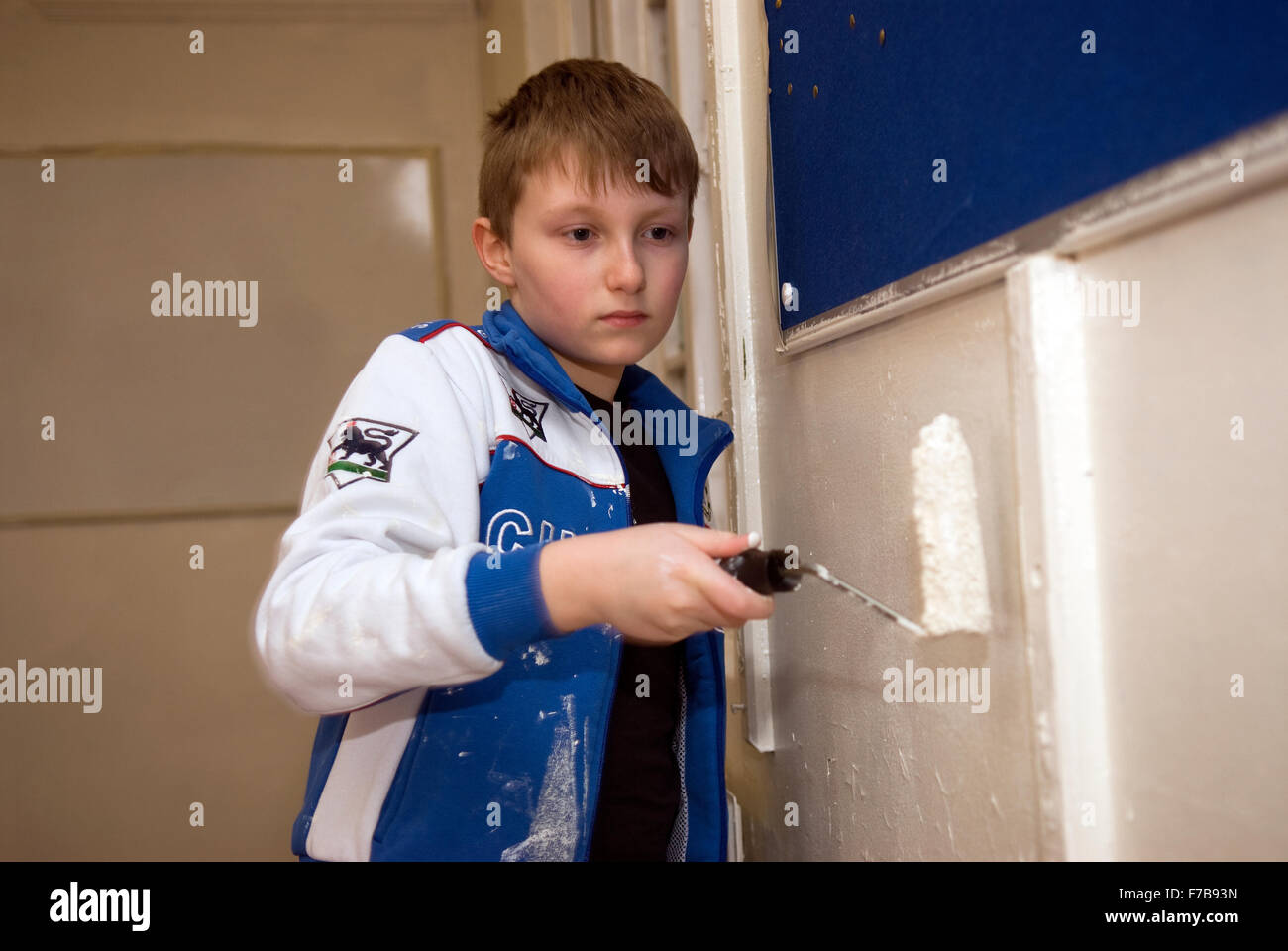 A 10 year old Scout with paint roller helping with the refurbishment of the new home for a local Scout group, Bordon, Hampshire, UK. Stock Photo
