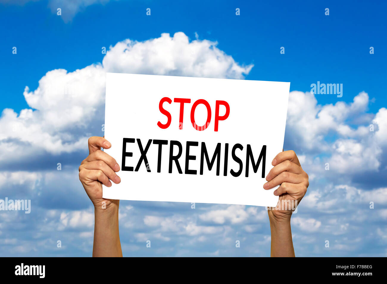 STOP EXTREMISM card in hand against blue sky with clouds. Selective focus. Stock Photo