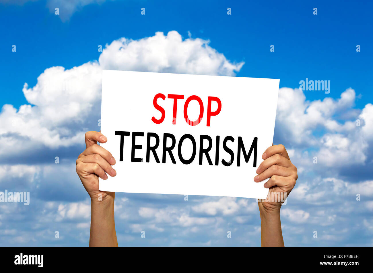 STOP TERRORISM card in hand against blue sky with clouds. Selective focus. Stock Photo