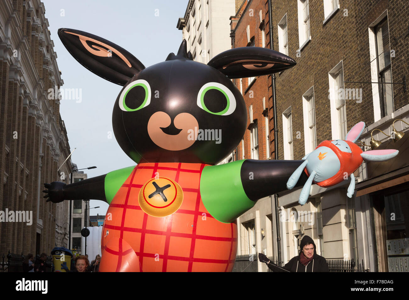 London, UK. 28 November 2015. Handlers manoeuvre a giant inflatable Bing  with his Hoppity Voosh toy through the narrow streets of Soho. The  inaugural Hamleys Christmas Toy Parade takes place along Regent