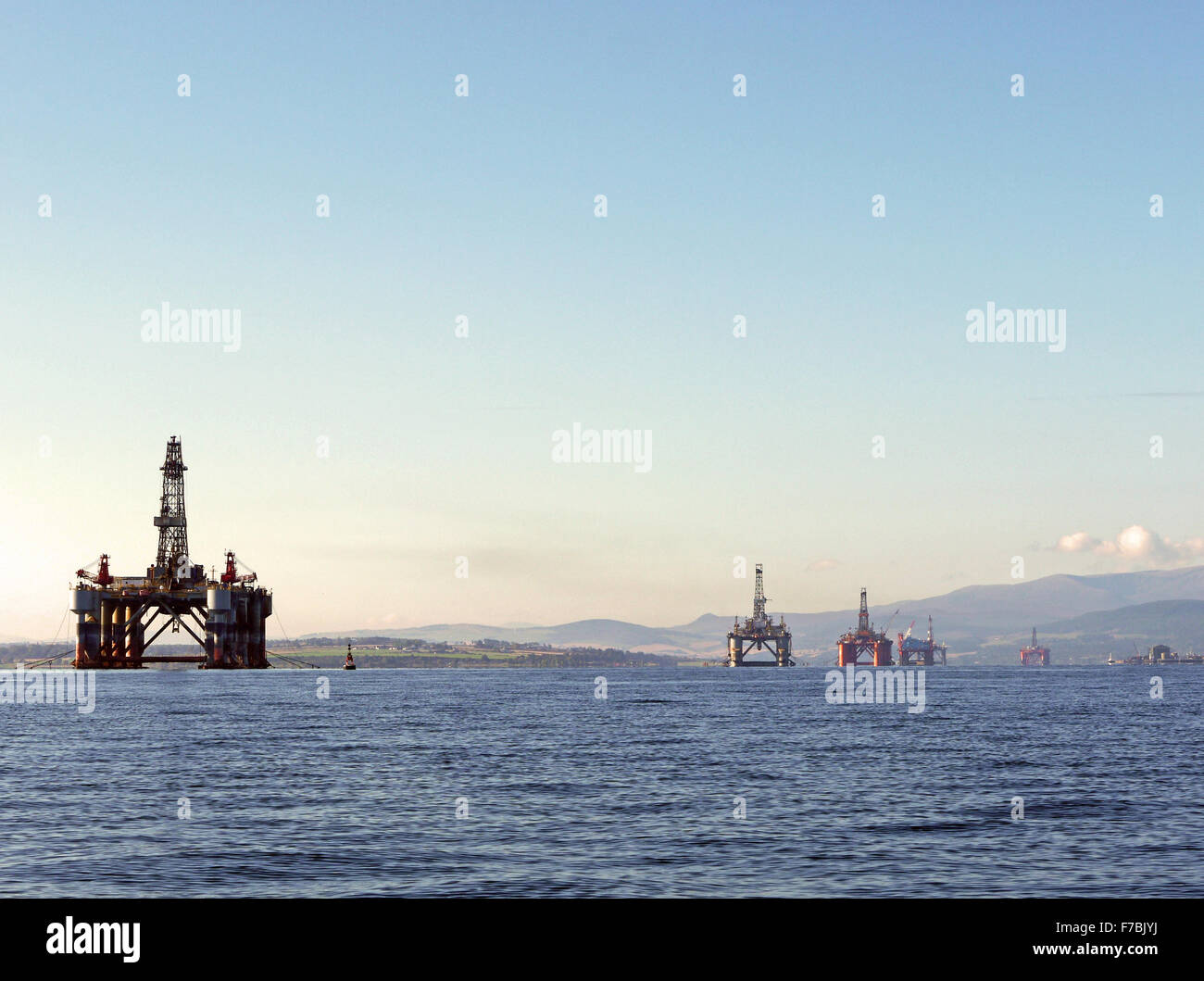 North Sea oli and gas rigs lined up in the sheltered waters of the Cromarty Firth for maintenance and refurbishment Stock Photo