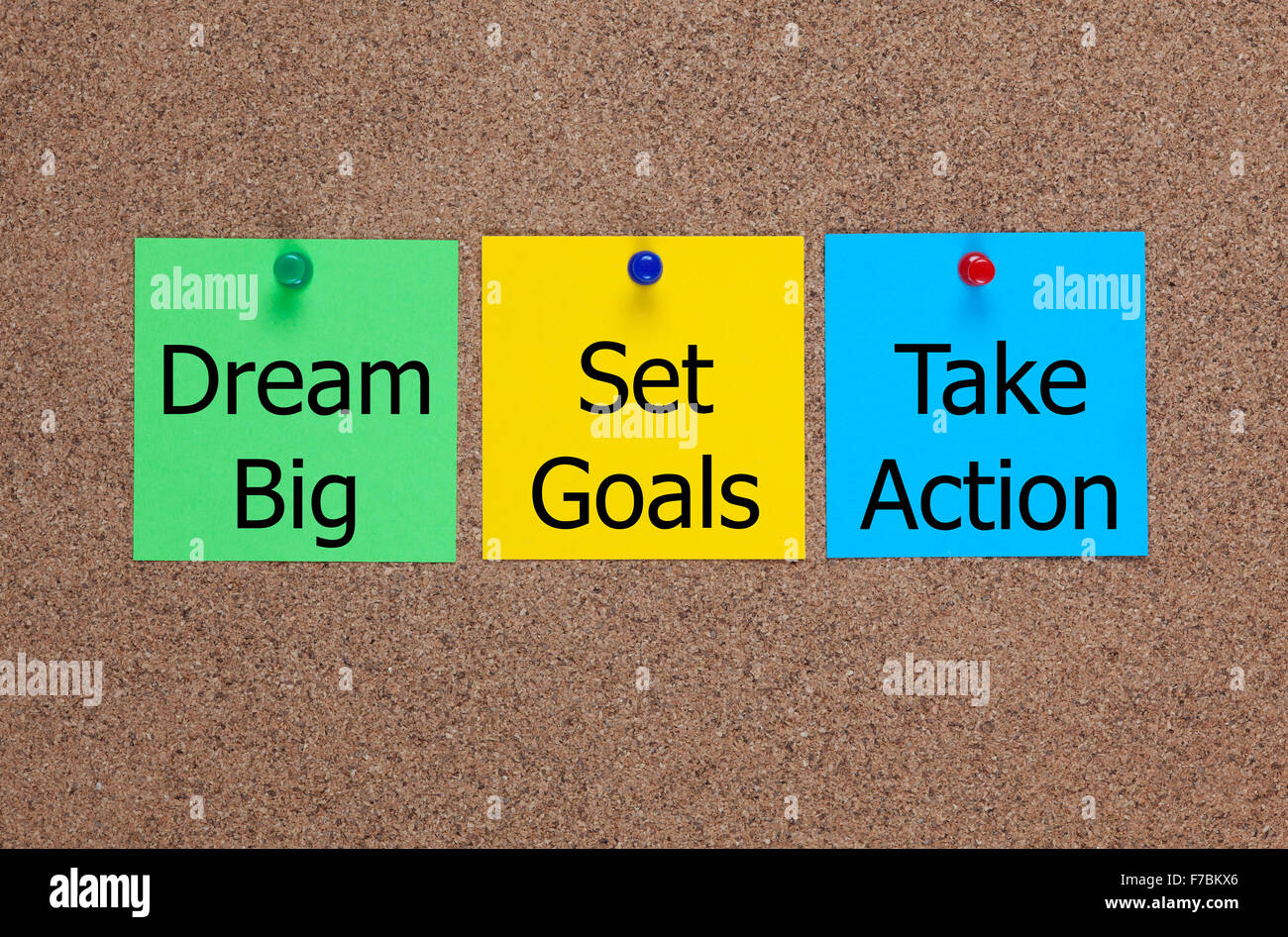 Three blanks post-it notes on cork board with words Dream Big, Set Goals, Take Action. Stock Photo