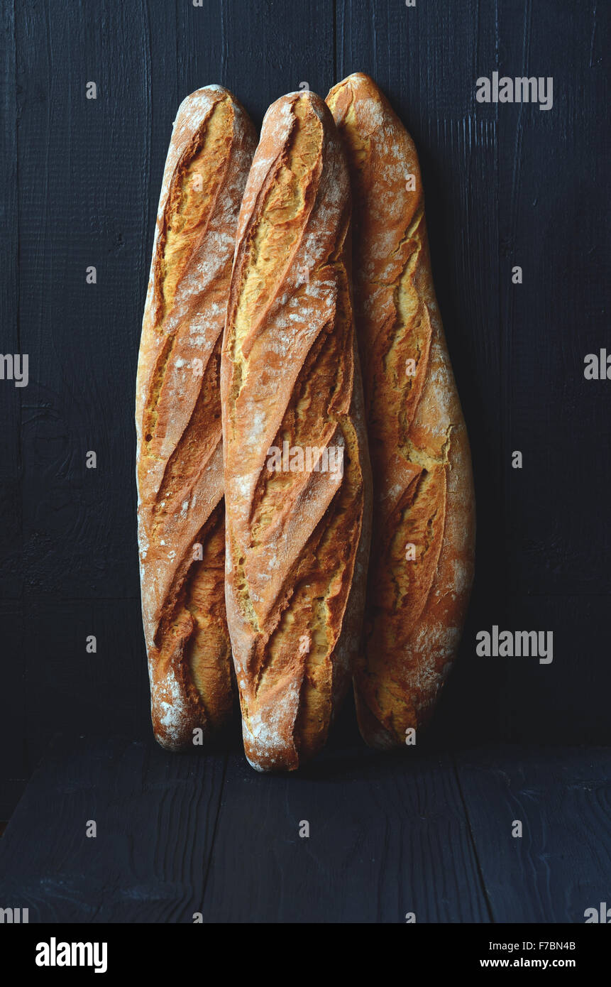 Fresh crispy baguette on dark wooden background Stock Photo