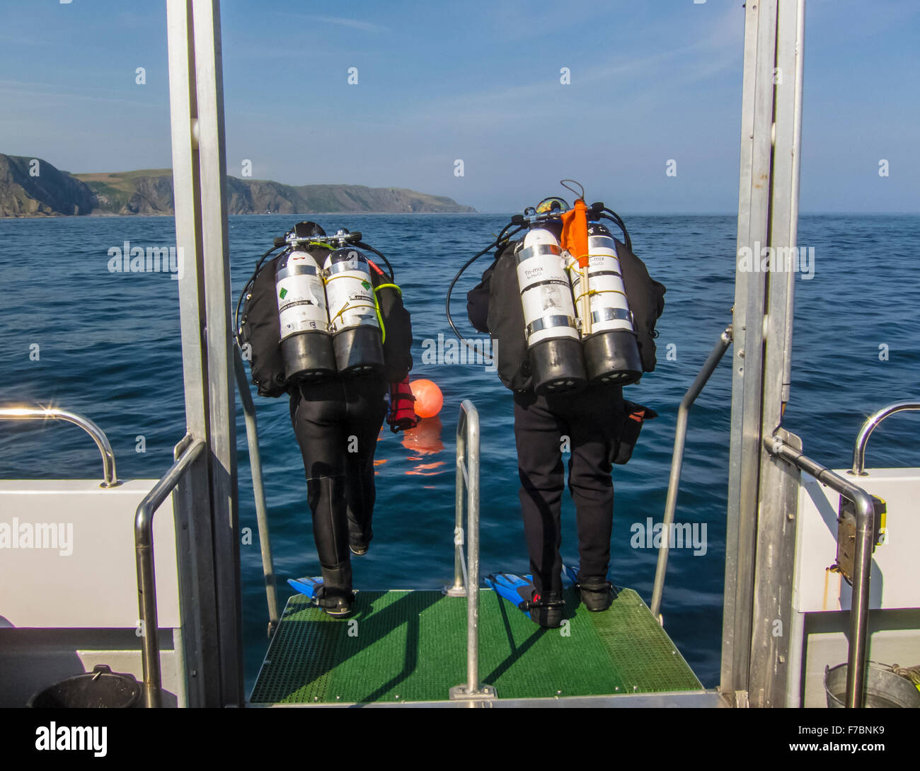 Scuba divers jump off the diving boat into the ocean, by St Abbs Scotland. Stock Photo