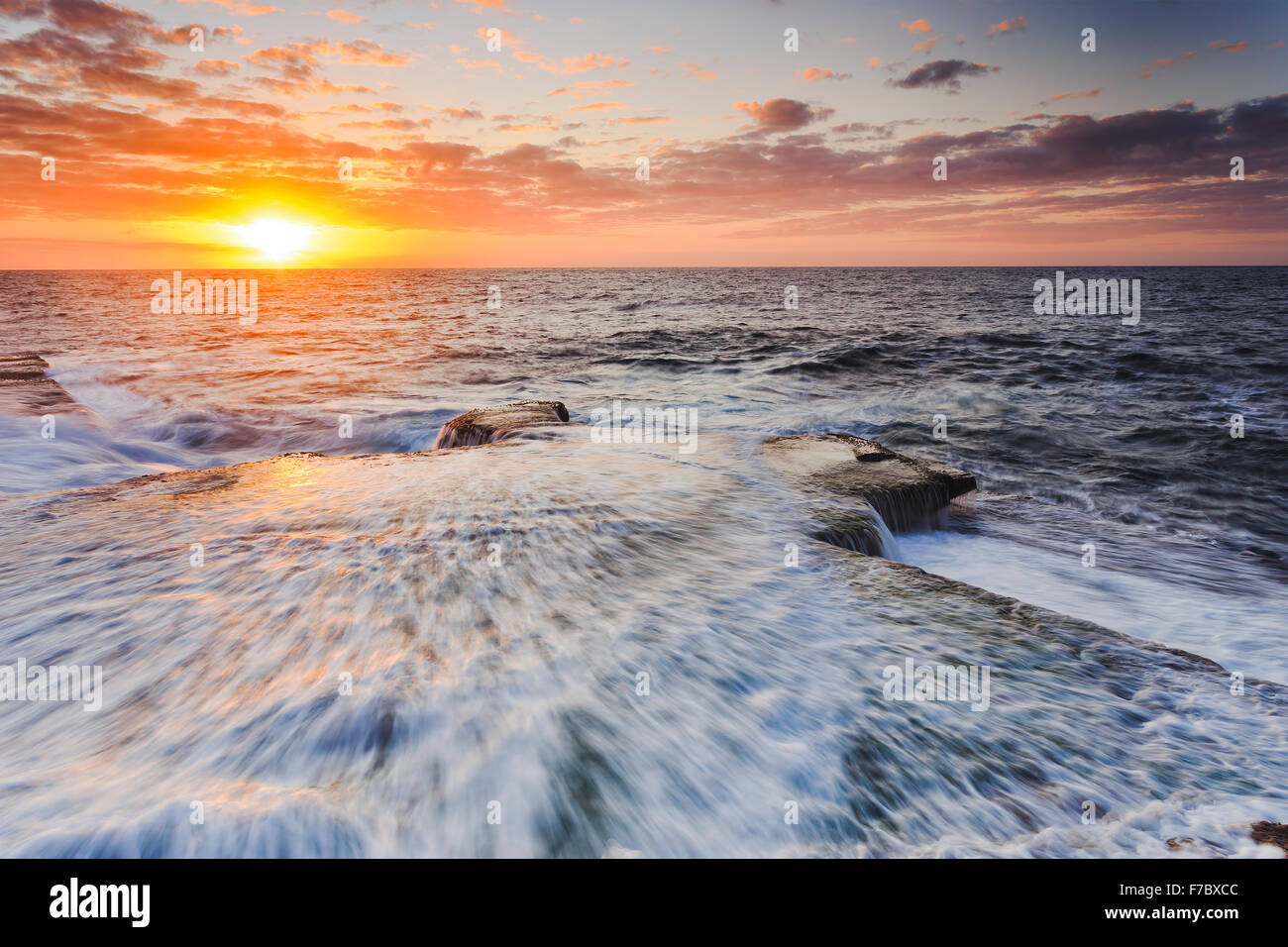 strong incoming wave over rocks near Sydney's Maroubra beach of Pacific coast at sunrise Stock Photo