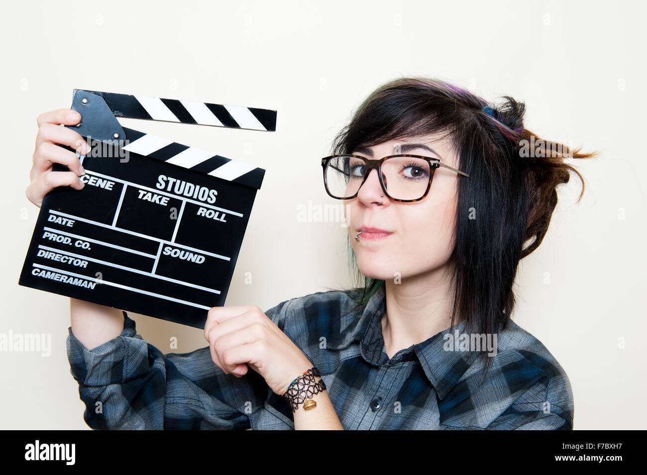 Pretty young alternative teen woman smiling and showing movie clapper Stock Photo
