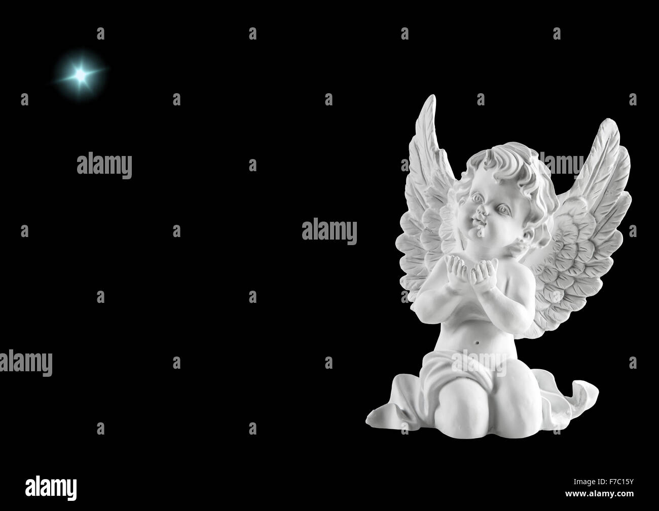 Little white guardian angel with star isolated on black background. Christmas decoration Stock Photo