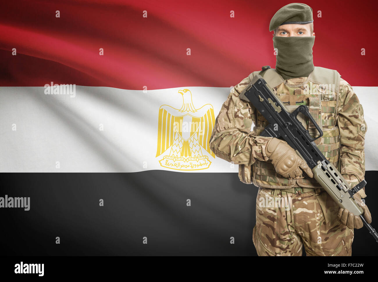 Soldier holding machine gun with national flag on background - Egypt ...