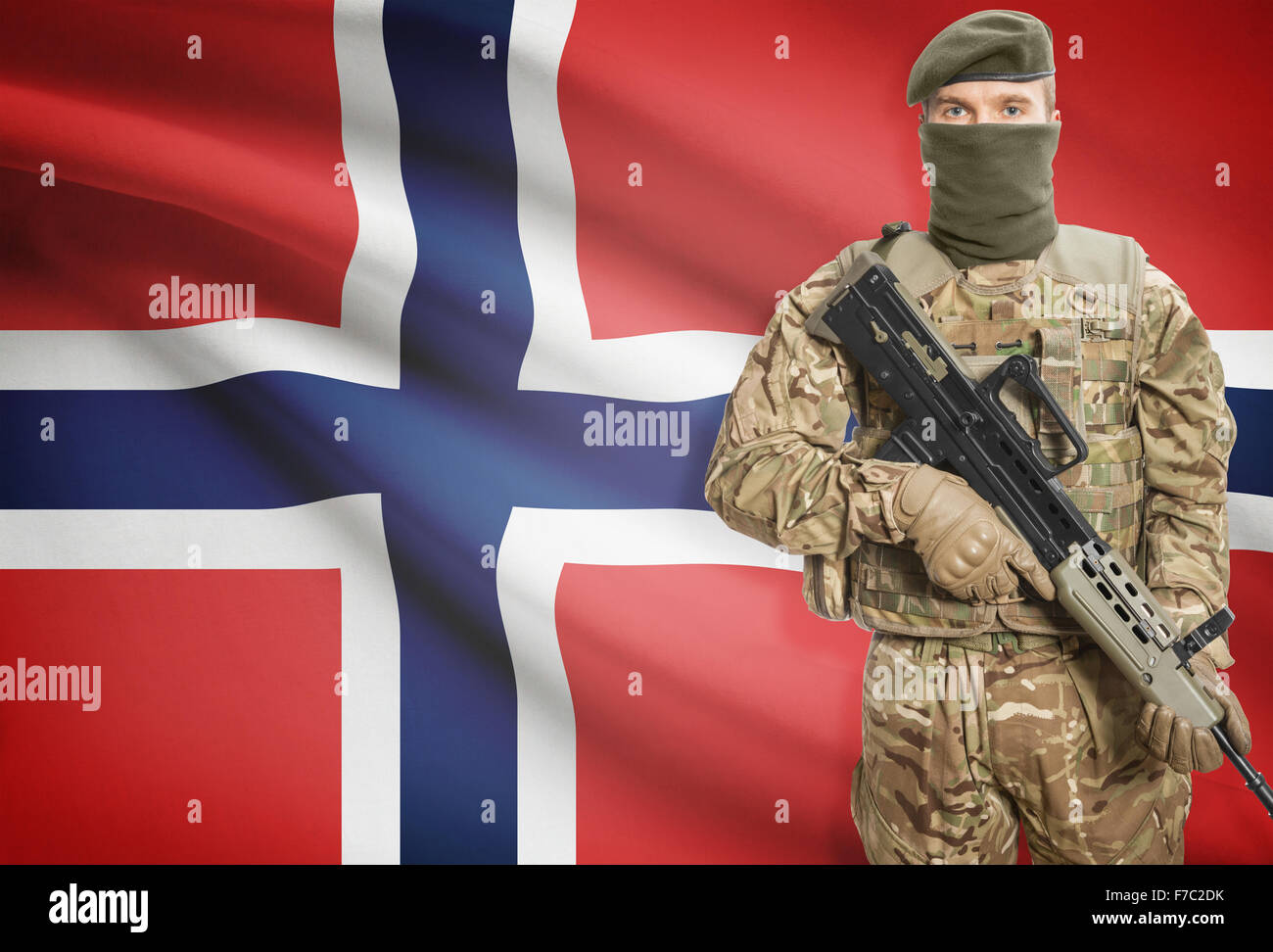 Soldier holding machine gun with national flag on background - Norway Stock Photo