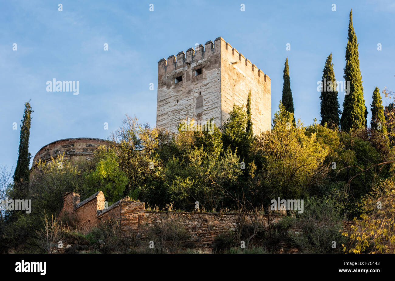 One of the towers of the Alhambra Palace in Granada Spain bathed in sun with the autumn leaves on the trees in the foreground. Stock Photo