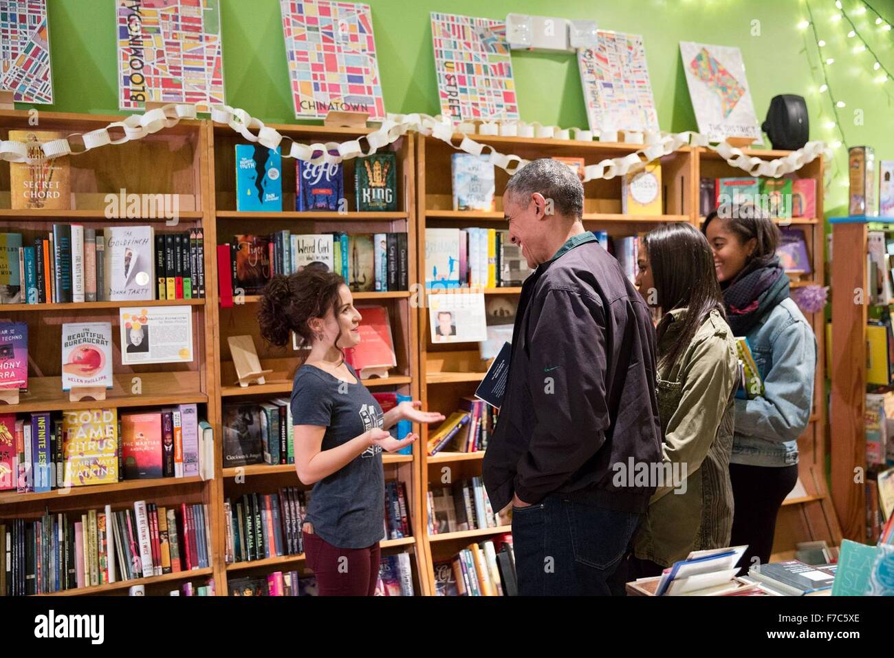 Washington, DC, USA. 28th Nov, 2015. U.S. President Barack Obama is assisted by manager Anna Thorn, left, as he shops at Upshur Street Books with daughters Malia and Sasha on Small Business Saturday November 28, 2015 in Washington, DC. Stock Photo