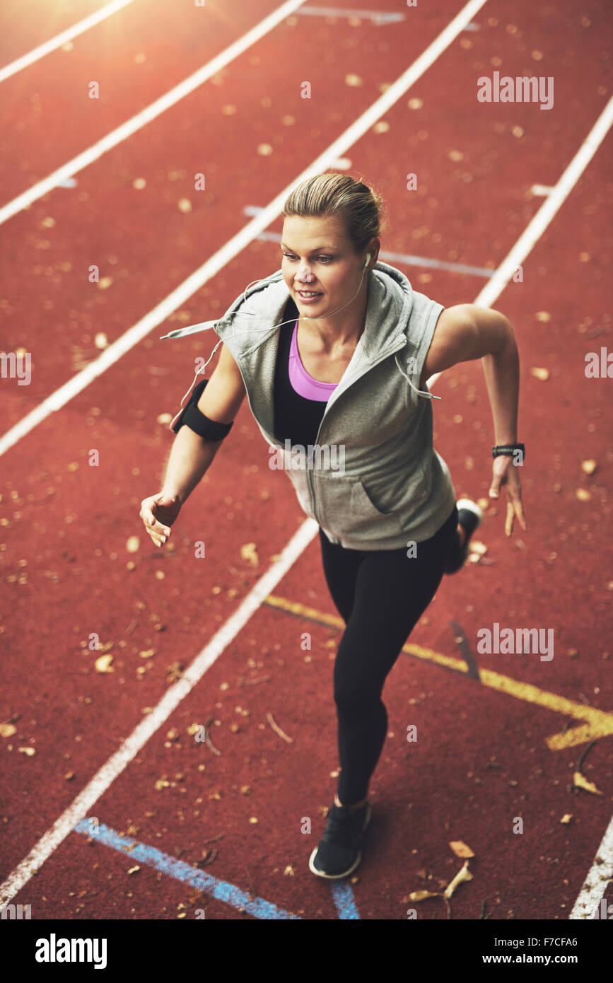 FIt young woman running on track field while listening to music Stock Photo