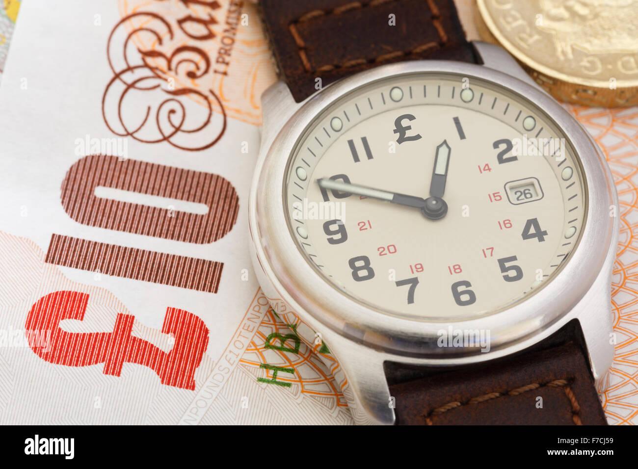 Wristwatch on a ten pound note and a coin to illustrate time is money and austerity concept. England, UK, Britain Stock Photo