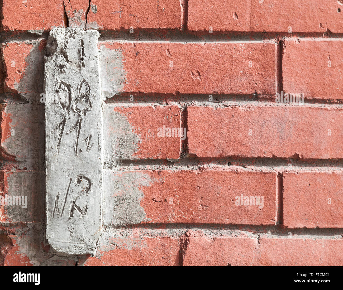 Special concrete block with installation date for observing cracks in red brick wall Stock Photo