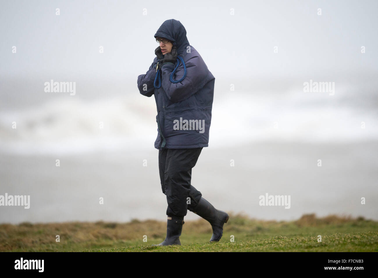 A walker is blown in strong winds during storm Clodagh at Porthcawl seafront, South Wales. Stock Photo