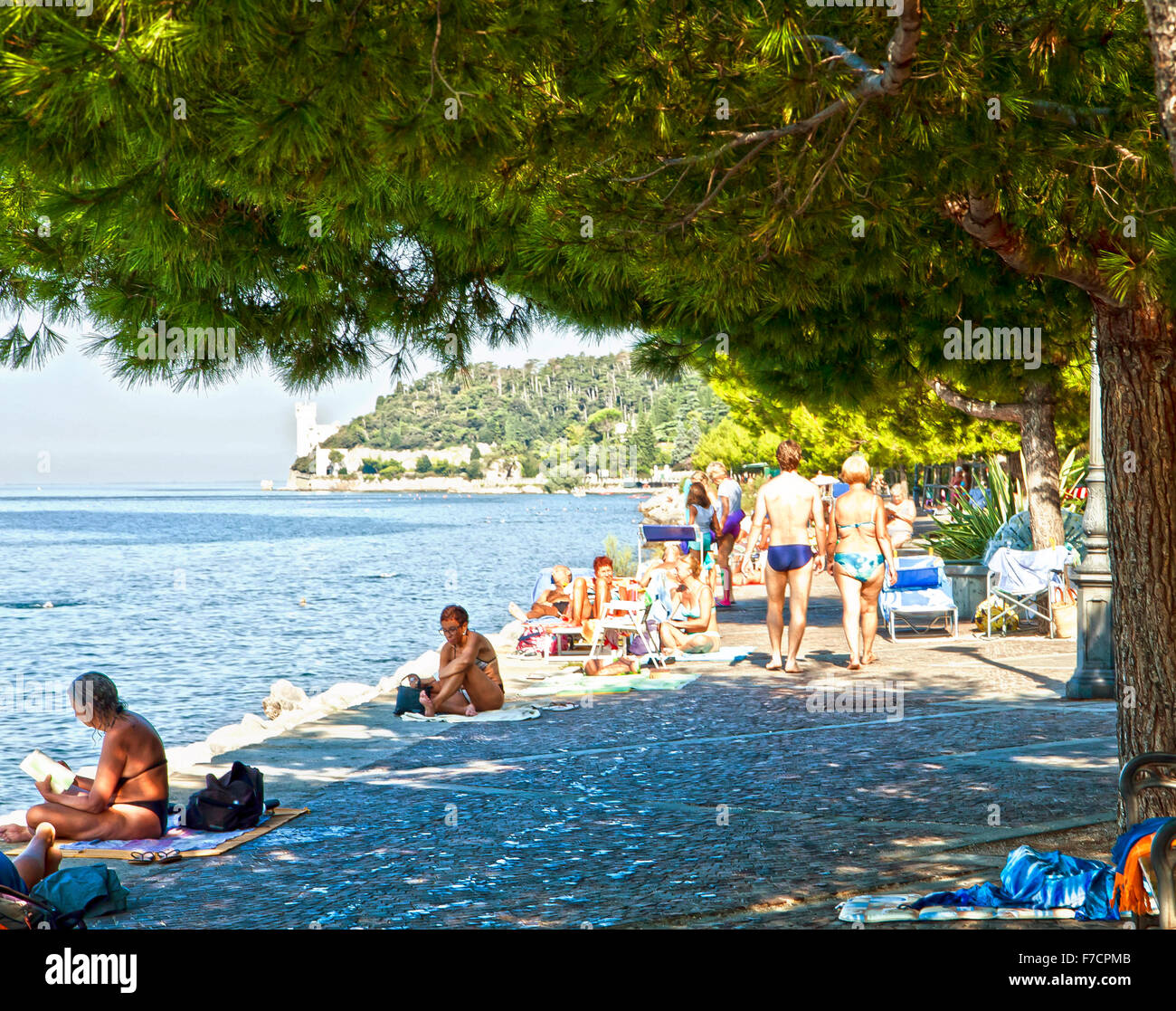 Trieste, Italy, beautiful summer view of Barcola promenade and free bathing strand with people sun bathing, relaxing, walking Stock Photo