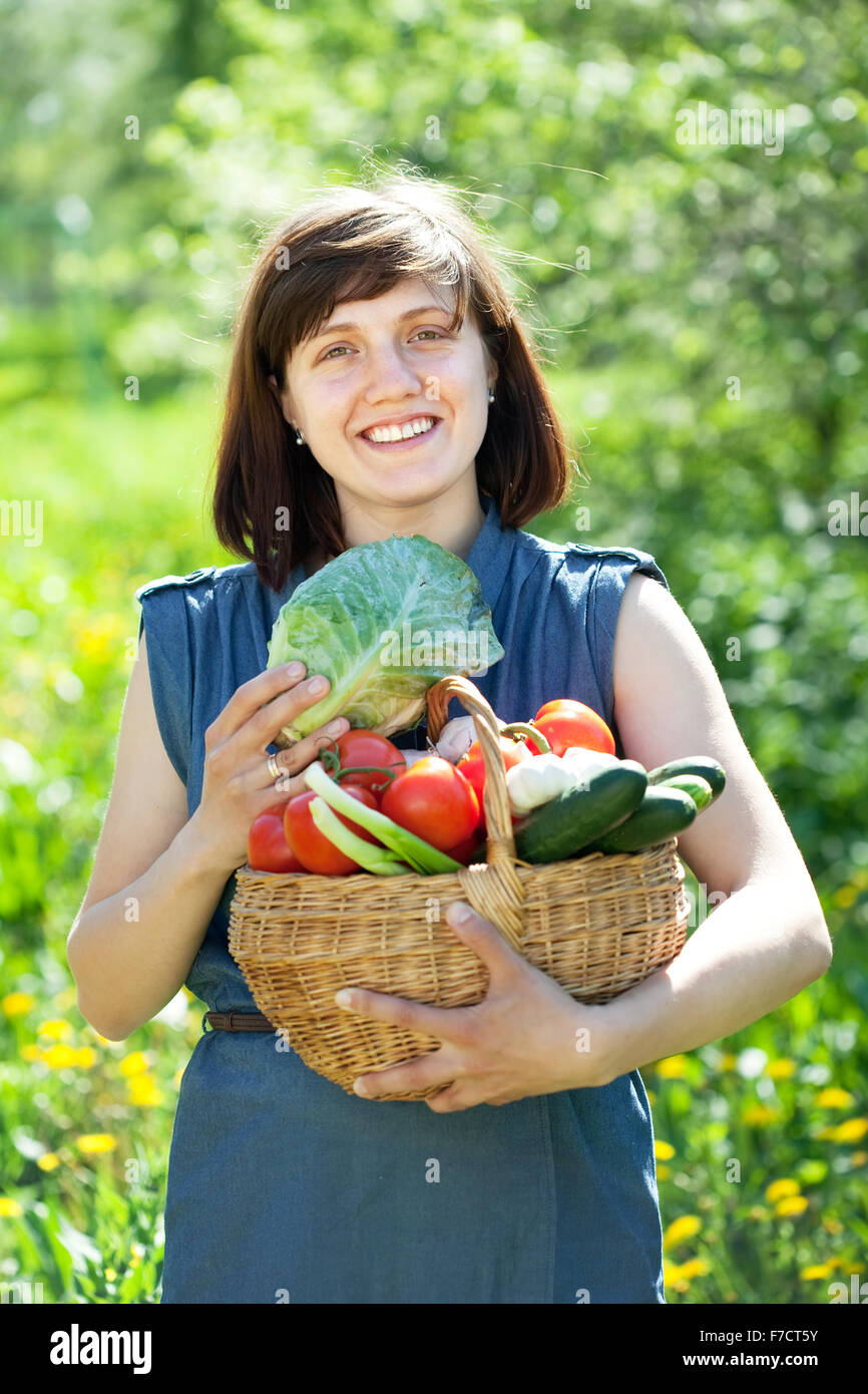 Happy young woman with basket of harvested vegetables in garden Stock ...