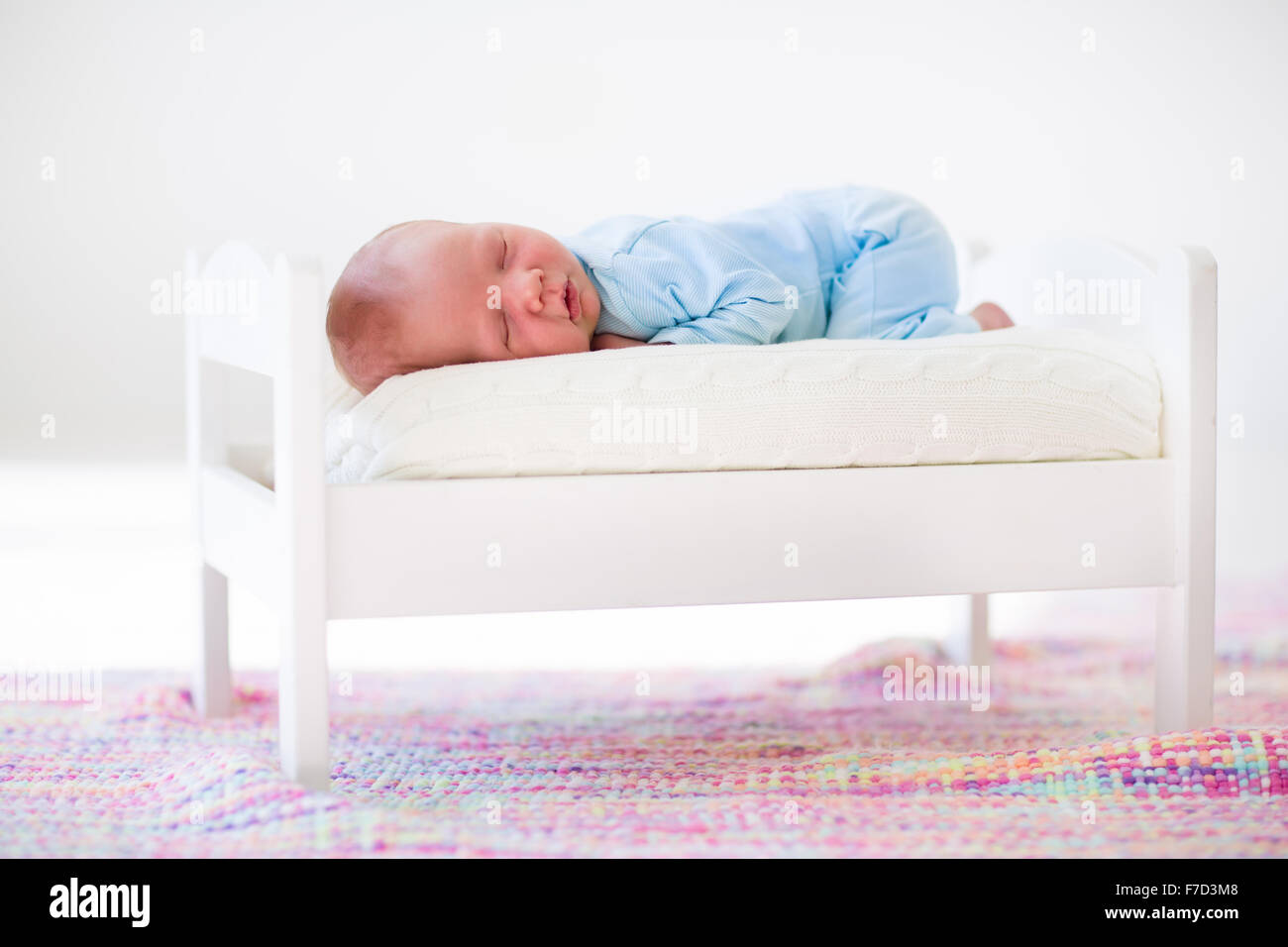 Adorable new born child sleeping in a white toy bed. Nursery for