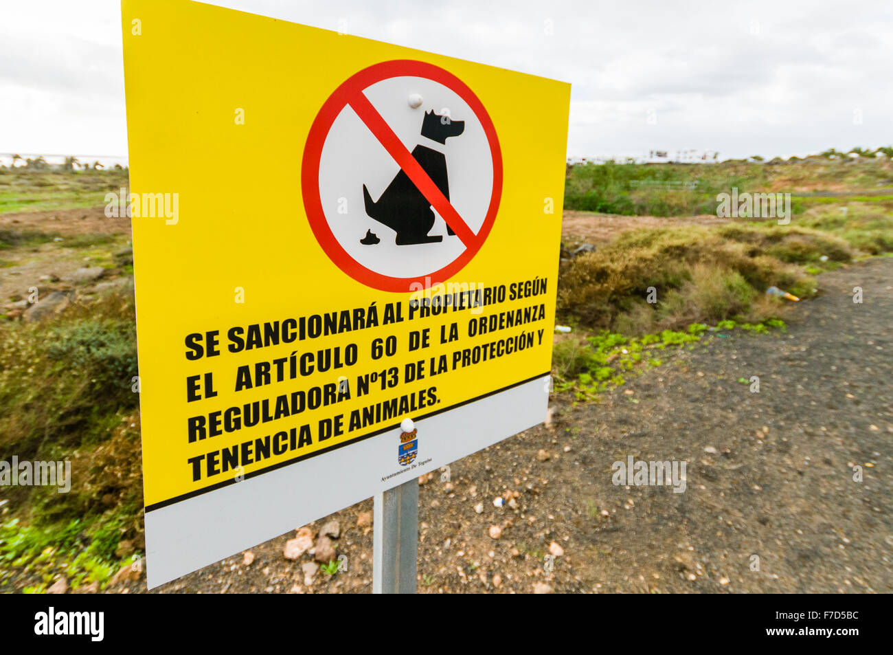 Sign in a Spanish park waring dog owners to clean up after their animals otherwise they will receive a fine Stock Photo