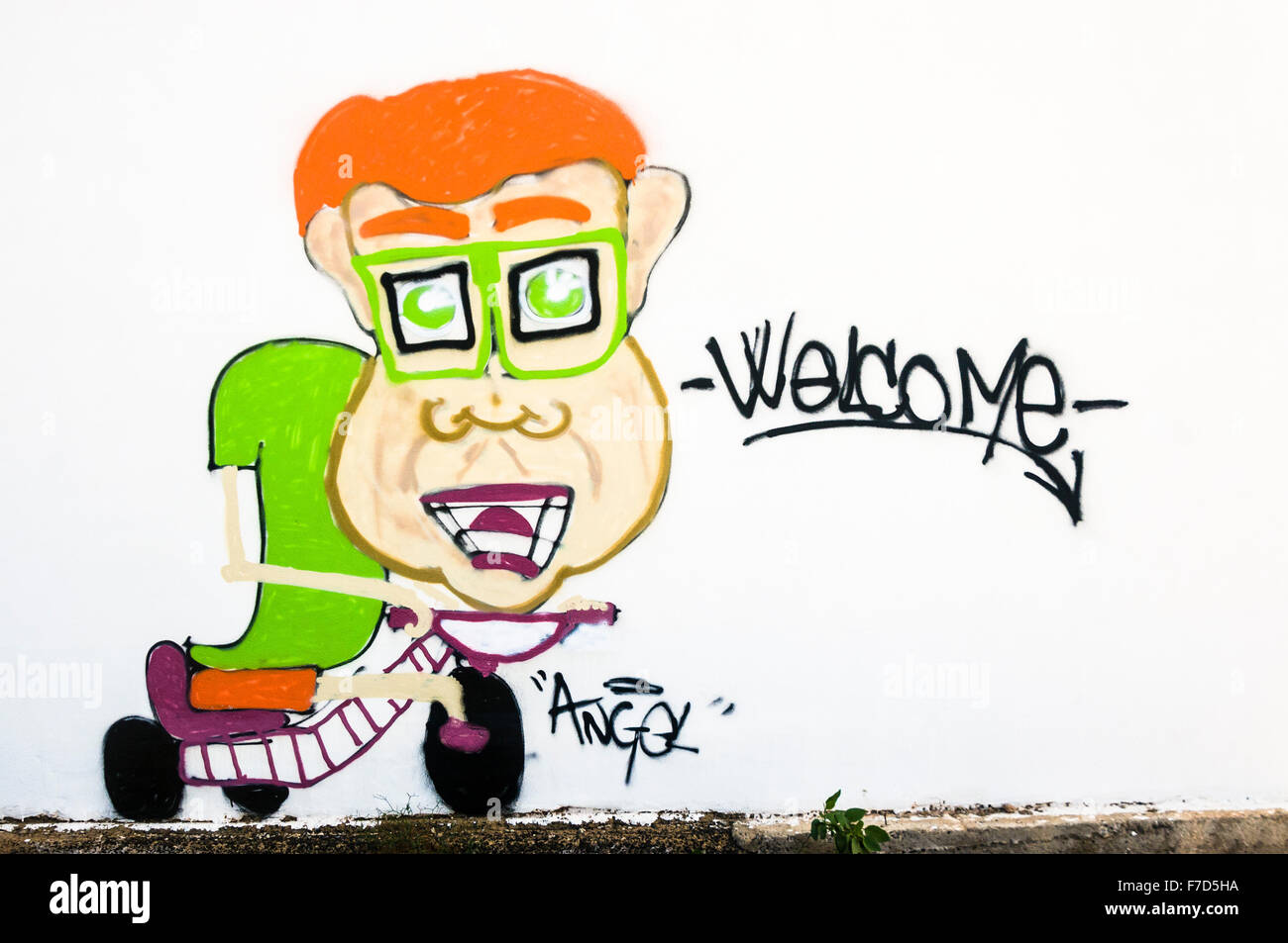 Graffiti painted on a white wall of a boy on a scooter saying 'Welcome' Stock Photo