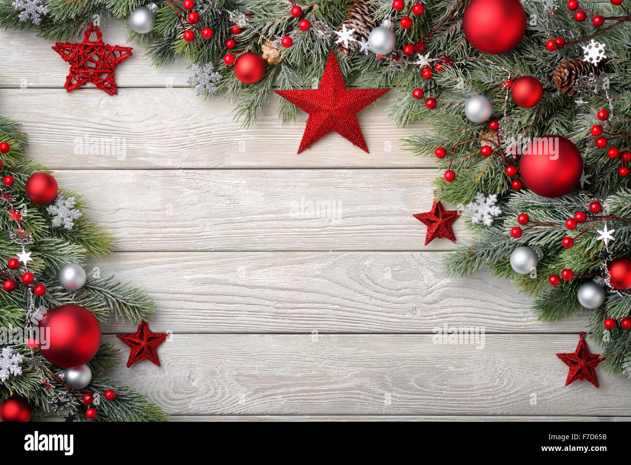 Christmas background with bright wooden board and fir branches decorated with red and silver baubles and stars - modern, simple Stock Photo