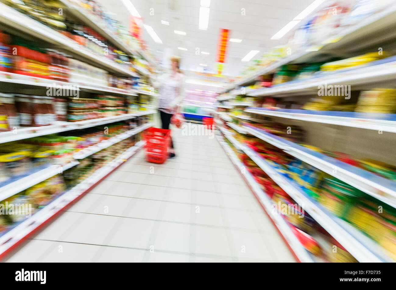 A woman lifts items off shelves in a Spanish supermarket (deliberately