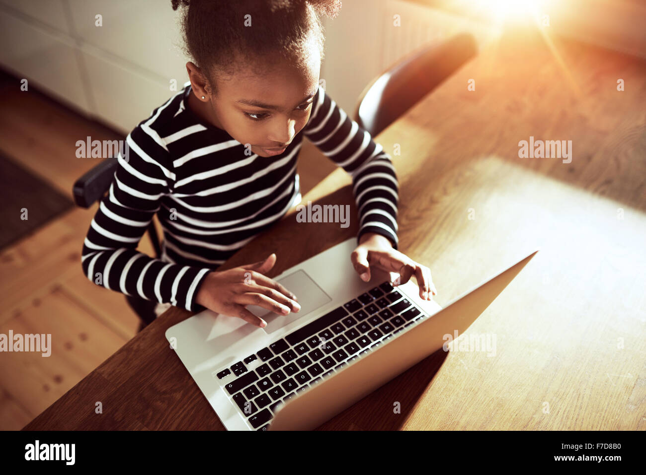 High angle view from above of a cute young African girl surfing the web on a laptop computer in an educational or recreational c Stock Photo
