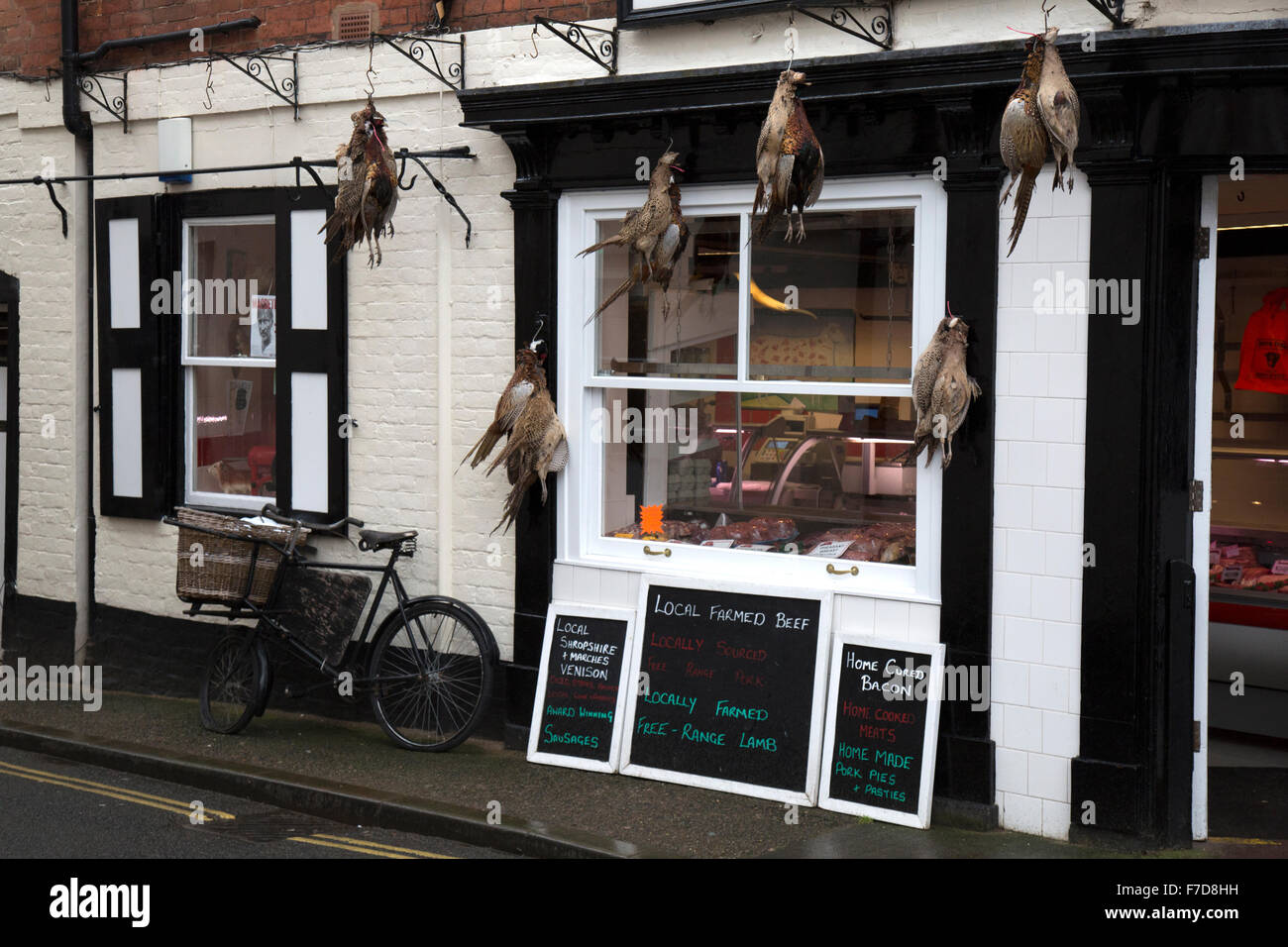 A traditional butchers shop selling game birds (pheasants), in Ludlow, Shropshire, England. Stock Photo