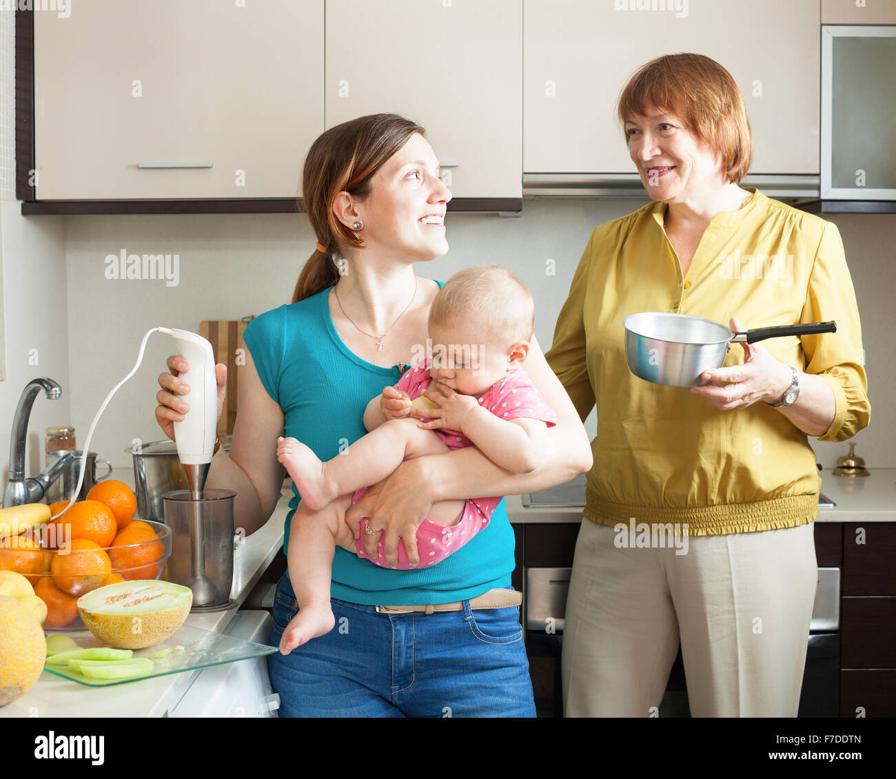 Happy women with child together cooking fruit puree  in kitchen at home Stock Photo