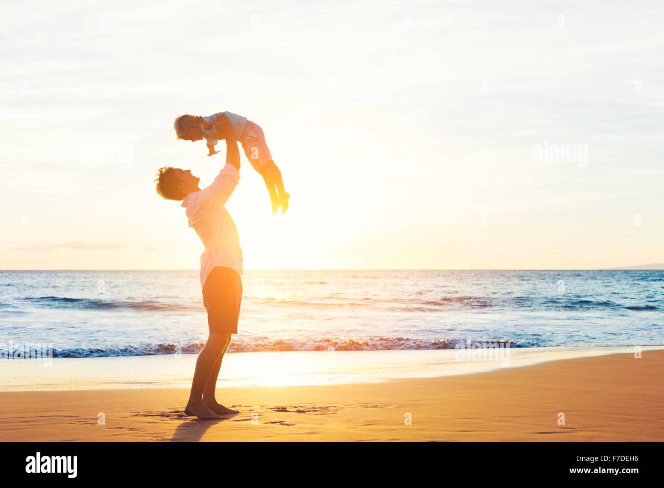 Happy Joyful Father and Son Having Fun Playing on the Beach at Sunset. Fatherhood Family Concept Stock Photo